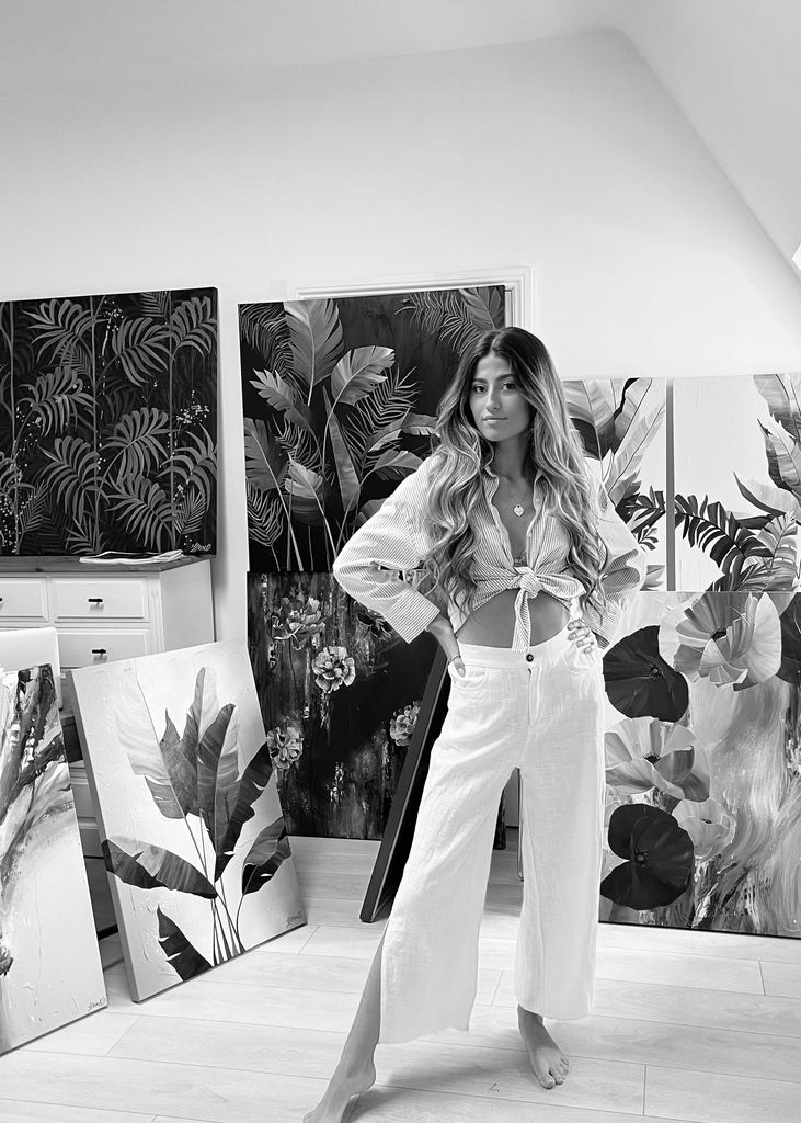 Artist Jasmine Marshall in the studio in black and white with paintings