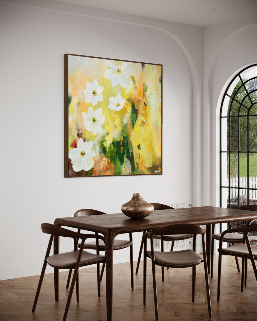 A 'Fresh Start' original acrylic painting by Jasmine Marshall framed in black/oak. Canvas painting features white anemone flowers atop cream, lime green, yellow, and brown abstract details, featured in a neutral home interior with a wooden dining room and glass doors.