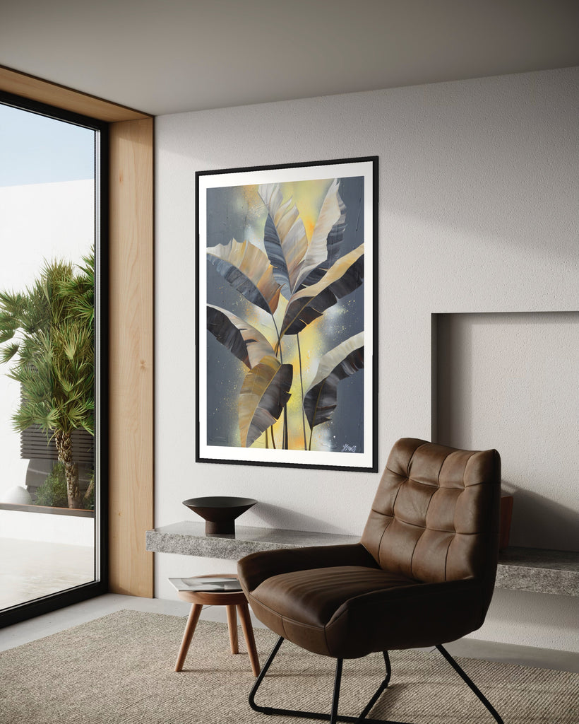 'Bittersweet' Fine Art Print by Jasmine Marshall, framed in black/oak. Premium Giclée print features grey palm leaves on an abstract yellow background. Featured in a neutral home interior and view of the garden.