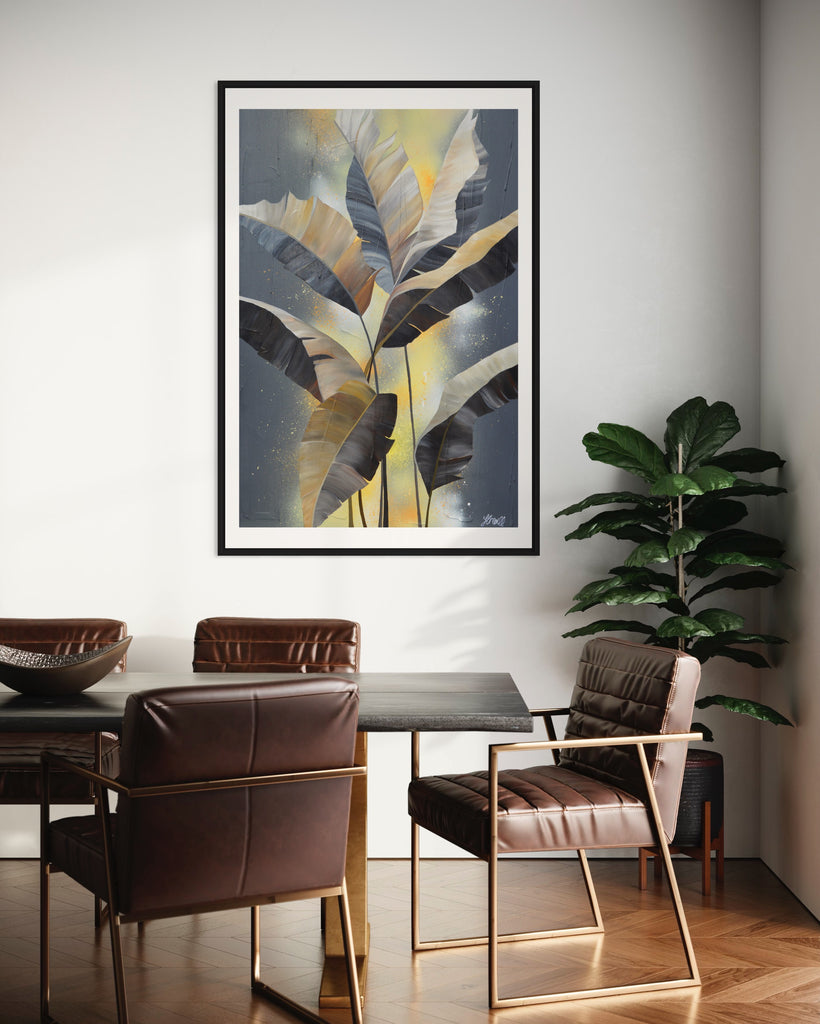 'Bittersweet' Fine Art Print by Jasmine Marshall, framed in black/oak. Premium Giclée print features grey palm leaves on an abstract yellow background. Featured in a neutral home interior with a dark brown dining table and plant.