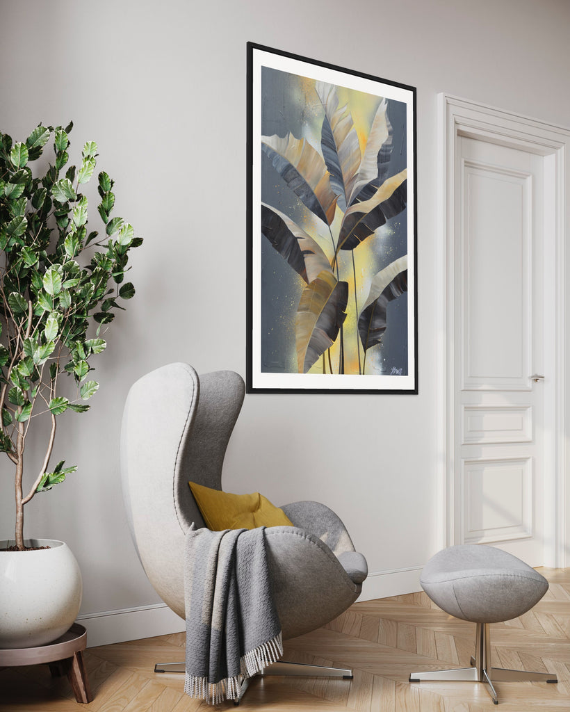 'Bittersweet' Fine Art Print by Jasmine Marshall, framed in black/oak. Premium Giclée print features grey palm leaves on an abstract yellow background. Featured in a neutral home interior with a grey sofa and yellow cushion with plant.