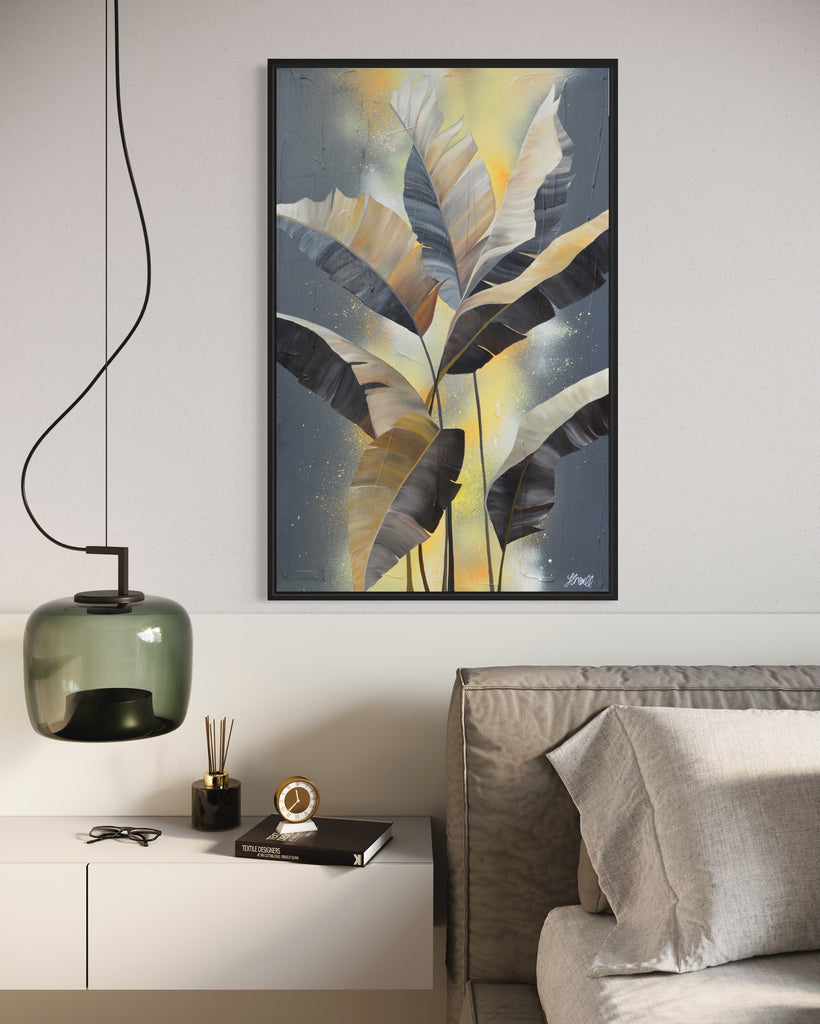 'Bittersweet' original acrylic painting by Jasmine Marshall framed in black/oak. Canvas painting features grey palm leaves on an abstract yellow background. Featured in a neutral home interior with a grey bed.