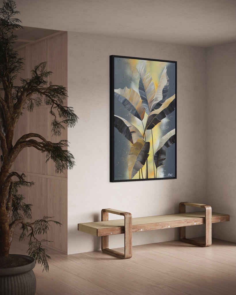 'Bittersweet' original acrylic painting by Jasmine Marshall framed in black/oak. Canvas painting features grey palm leaves on an abstract yellow background. Featured in a neutral home interior with a plant and wooden bench..