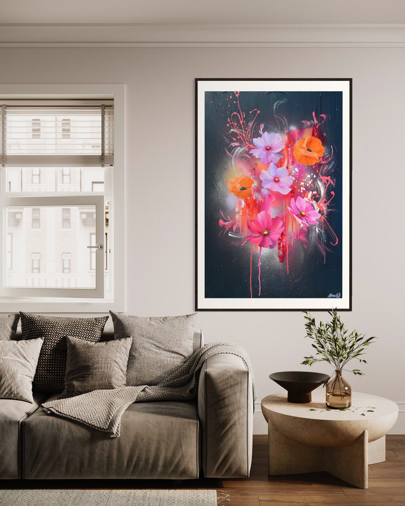 A 'Drama Tropicana' Fine Art Print by Jasmine Marshall, framed in black/oak. Premium Giclée print features white orange poppies and pink and purple flower on an abstract navy background, featured in a neutral home interior  with grey sofa and wooden coffee table.