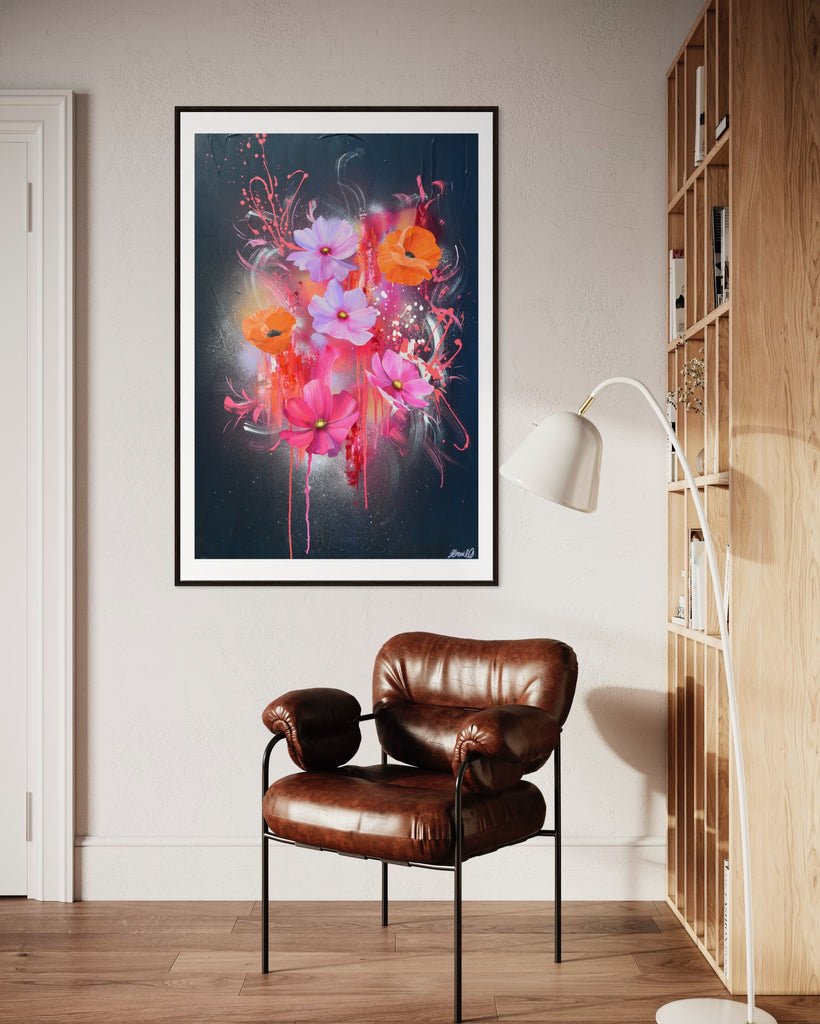 A 'Drama Tropicana' Fine Art Print by Jasmine Marshall, framed in black/oak. Premium Giclée print features white orange poppies and pink and purple flower on an abstract navy background, featured in a neutral home interior with a wooden book shelf, brown leather chair and white standing lamp.