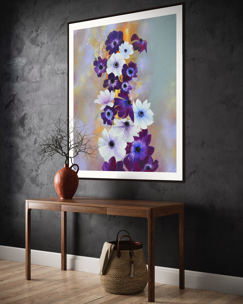 ‘Flourish' Fine Art Print by Jasmine Marshall, framed in black/oak. Premium Giclée print features white and purple anemone flowers on a grey and lilac abstract background, featured on a grey wall with wooden side table and plant..