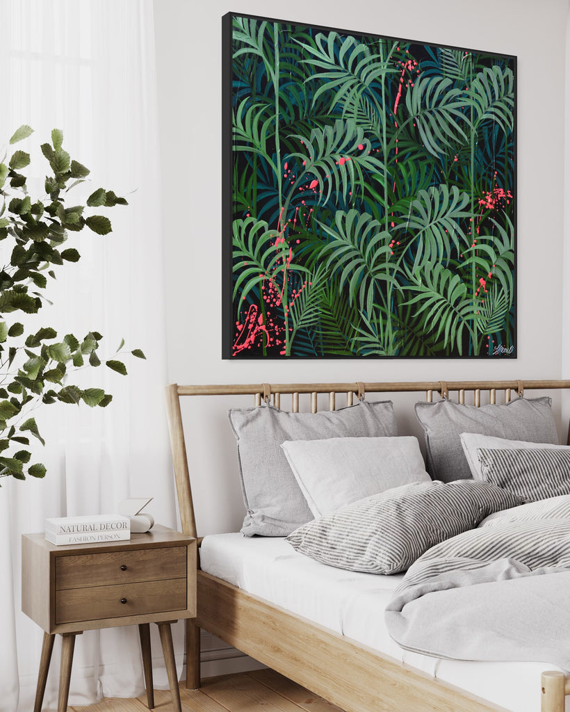 'Forever Green' original painting on a cotton canvas by Jasmine Marshall, framed in black/oak. Features layers of palm leaves on a black background with pops on neon pink.  Displayed in a neutral home interior. above a wooden bed frame with white sheets.