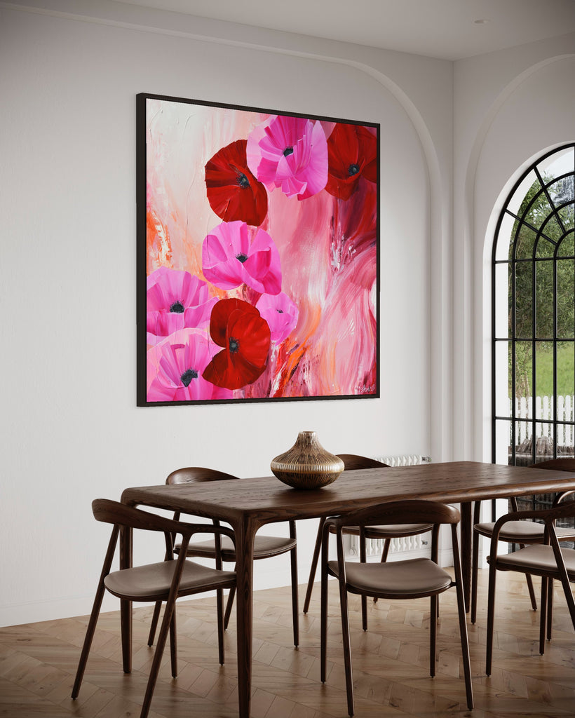 'It’s a Forever Thing' original painting on a cotton canvas by Jasmine Marshall, framed in black/oak. Features pink and red poppies on an abstract background with pops of orange. Displayed in a neutral home interior. with wooden dining table and glass window.