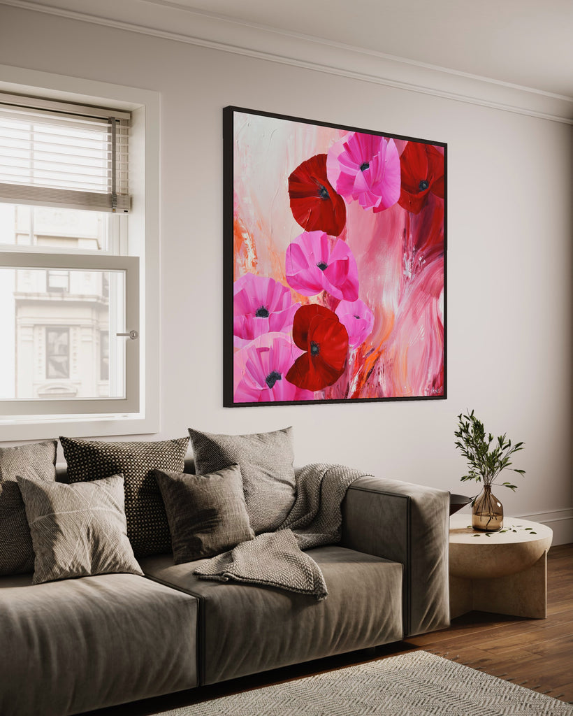 'It’s a Forever Thing' original painting on a cotton canvas by Jasmine Marshall, framed in black/oak. Features pink and red poppies on an abstract background with pops of orange. Displayed in a living room with a grey sofa and wooden coffee table.