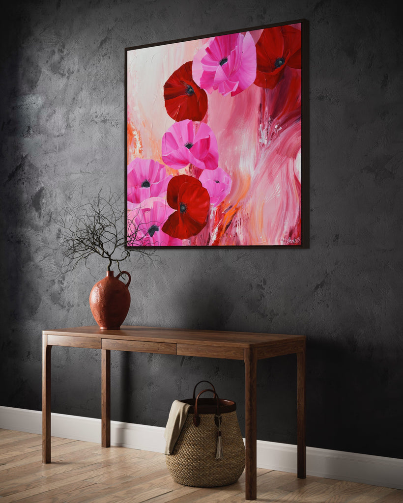 'It’s a Forever Thing' original painting on a cotton canvas by Jasmine Marshall, framed in black/oak. Features pink and red poppies on an abstract background with pops of orange. Displayed on a dark grey wall with wooden side table.