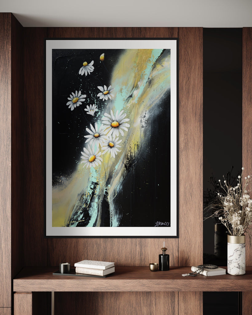 ‘Light in the Darkness' Fine Art Print by Jasmine Marshall, framed in black/oak. Premium Giclée print features white daisies on a black abstract background.  Displayed on a wooden wall with flowers.