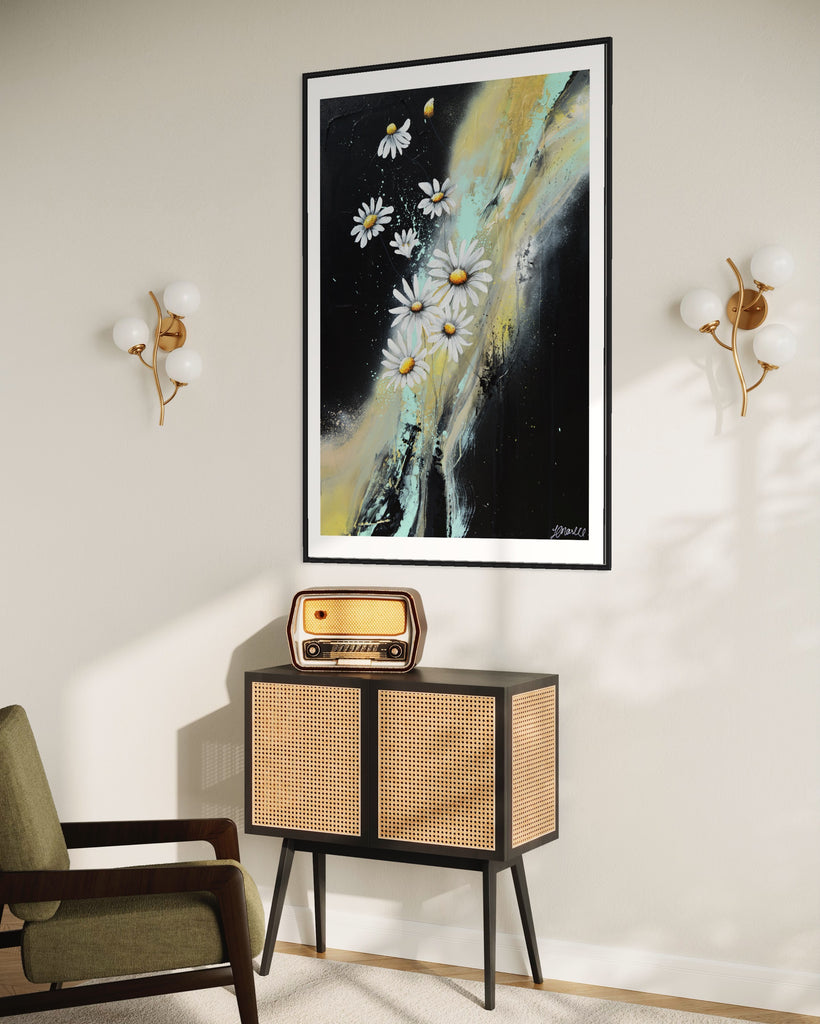 ‘Light in the Darkness' Fine Art Print by Jasmine Marshall, framed in black/oak. Premium Giclée print features white daisies on a black abstract background.  Displayed in a neutral home interior with green chair and stereo radio.