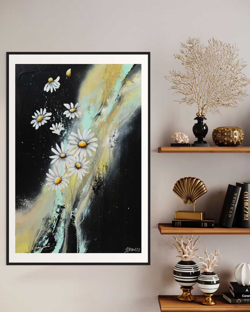 ‘Light in the Darkness' Fine Art Print by Jasmine Marshall, framed in black/oak. Premium Giclée print features white daisies on a black abstract background.  Displayed in a neutral home interior with black and gold shelves.