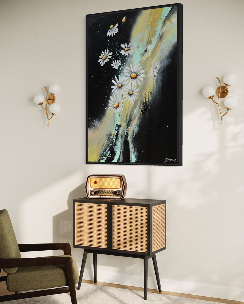 'Light in the Darkness' original painting on a cotton canvas by Jasmine Marshall, framed in black/oak. Features white daisies on a black abstract background. Displayed in a neutral home interior.