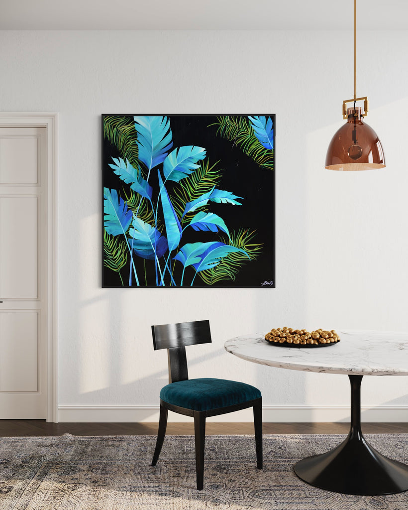 'Midnight Jungle' original painting on a cotton canvas by Jasmine Marshall, framed in black/oak. Features turquoise palm leaves on a black background. Displayed in a neutral home interior with rose gold lamp and marble table with blue chair.