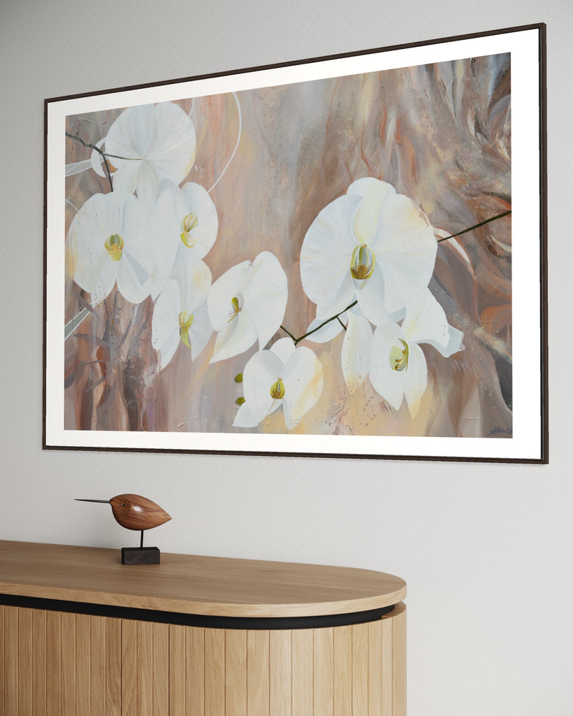 ‘Natural Elegance' Fine Art Print by Jasmine Marshall, framed in black/oak. Premium Giclée print features white orchids on a neutral brown, beige abstract background. Displayed in a neutral home interior above a wooden side table.