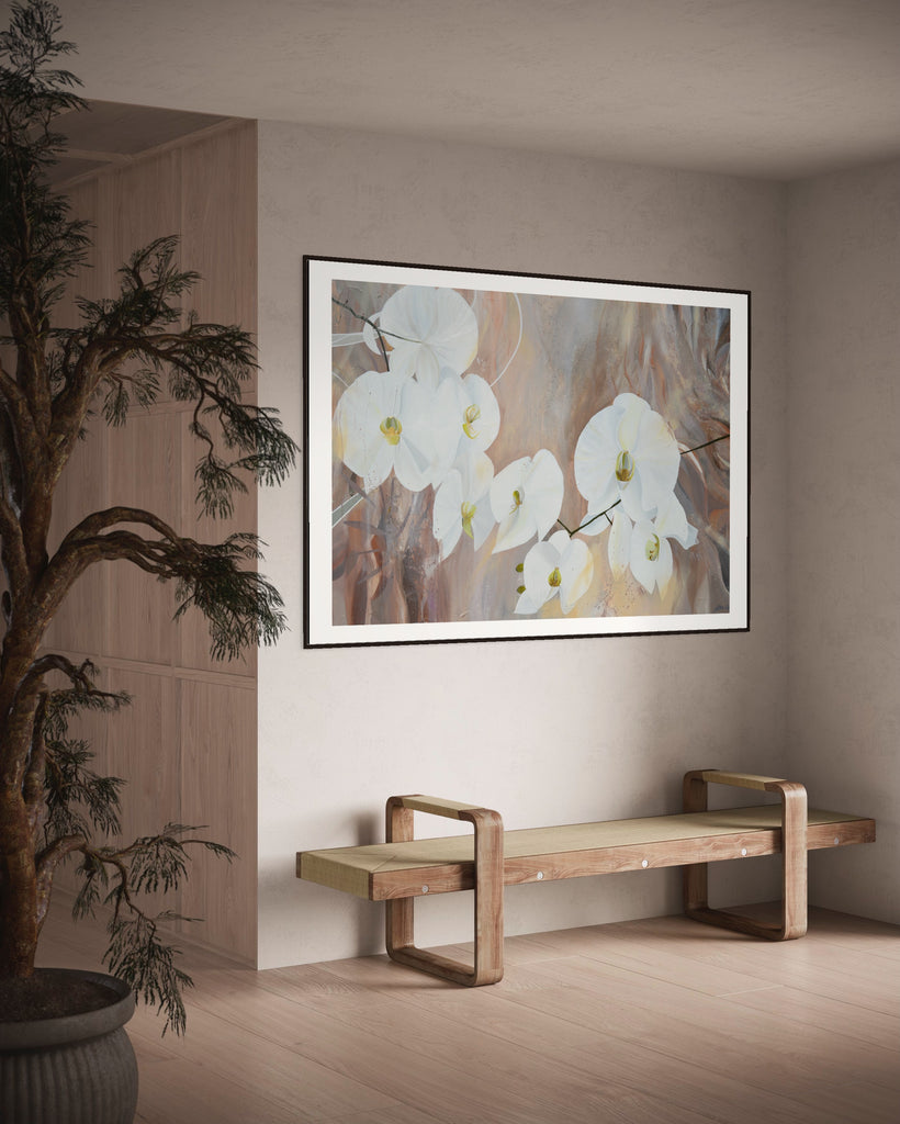 ‘Natural Elegance' Fine Art Print by Jasmine Marshall, framed in black/oak. Premium Giclée print features white orchids on a neutral brown, beige abstract background. Displayed in a neutral home interior with wooden bench and tree.