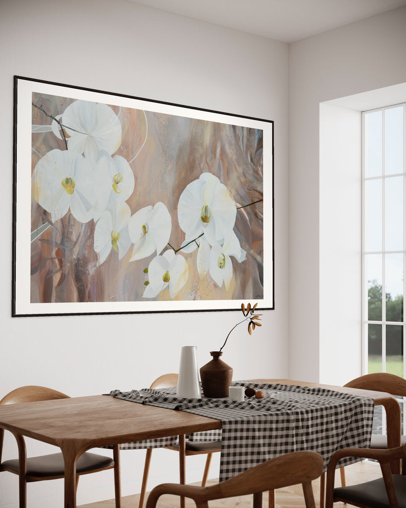 ‘Natural Elegance' Fine Art Print by Jasmine Marshall, framed in black/oak. Premium Giclée print features white orchids on a neutral brown, beige abstract background. Displayed in a neutral home interior with wooden dining table.