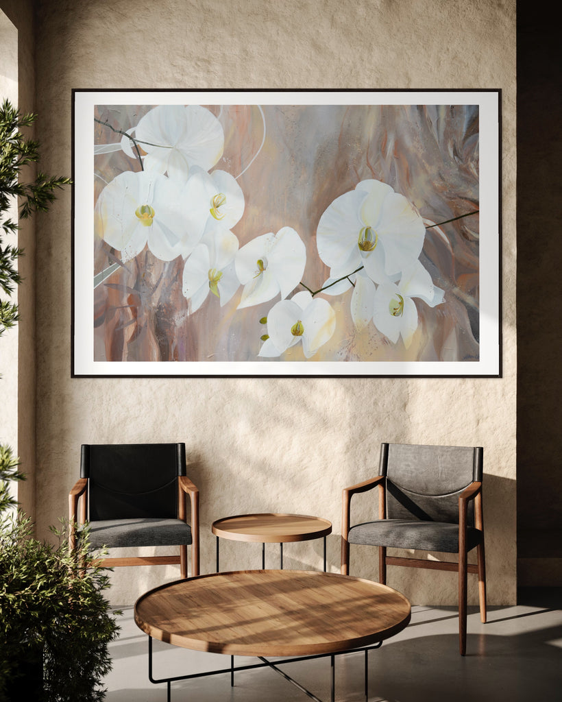 ‘Natural Elegance' Fine Art Print by Jasmine Marshall, framed in black/oak. Premium Giclée print features white orchids on a neutral brown, beige abstract background. Displayed in a neutral home interior with two chairs, wooden table and tree.