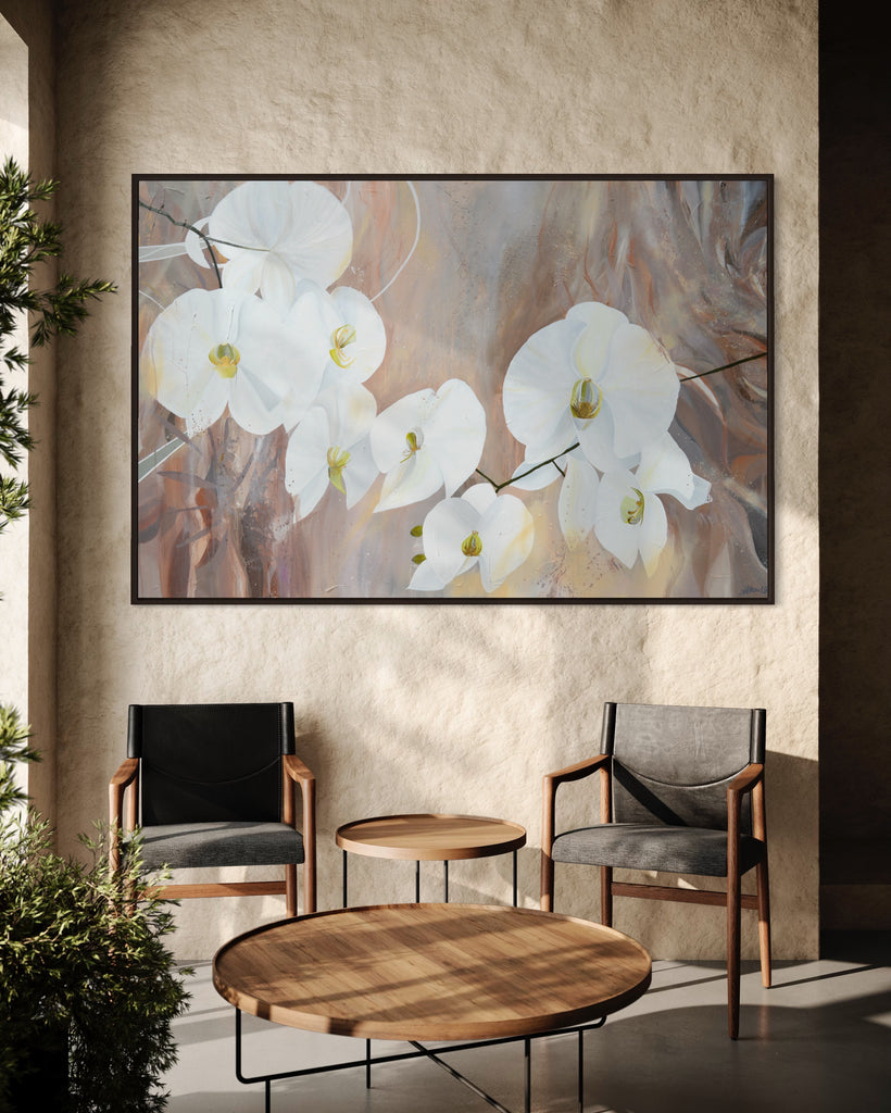 'Natural Elegance' original painting on a cotton canvas by Jasmine Marshall, framed in black/oak. Features white orchids on a neutral brown, beige abstract background. Displayed in a neutral home interior with wooden table and chairs and tree.