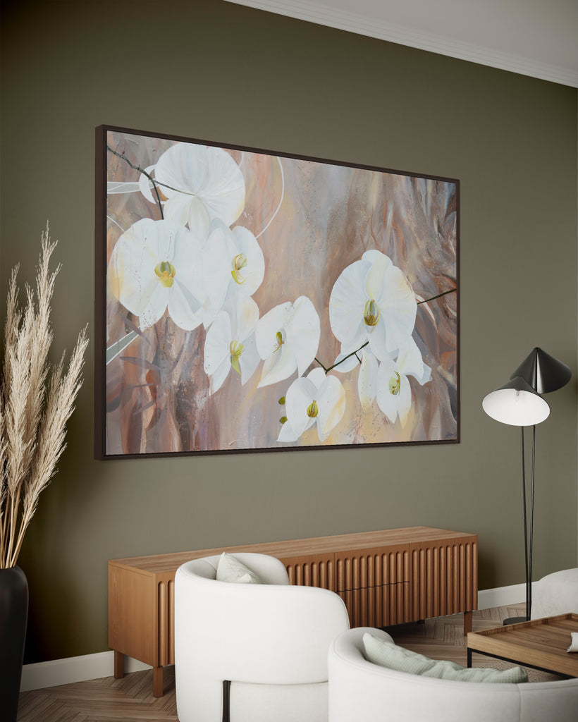 'Natural Elegance' original painting on a cotton canvas by Jasmine Marshall, framed in black/oak. Features white orchids on a neutral brown, beige abstract background. Displayed in a lounge with khaki wall and white chairs.