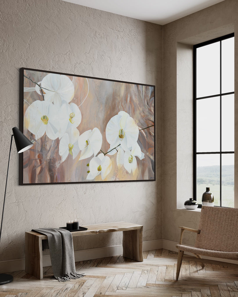 'Natural Elegance' original painting on a cotton canvas by Jasmine Marshall, framed in black/oak. Features white orchids on a neutral brown, beige abstract background. Displayed in a neutral home interior with big window, wooden bench and chair.