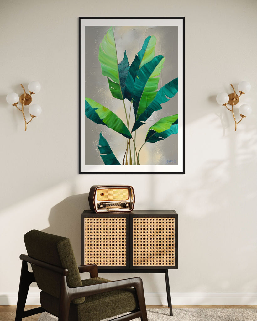 ‘Rainforest Glow' Fine Art Print by Jasmine Marshall, framed in black/oak. Premium Giclée print features green palm leaves on a neutral abstract painting. Displayed in a neutral home interior with a black side table with old stereo on.