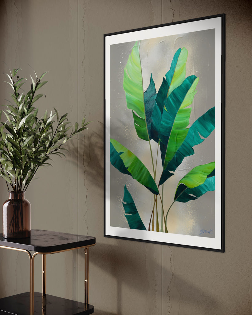 ‘Rainforest Glow' Fine Art Print by Jasmine Marshall, framed in black/oak. Premium Giclée print features green palm leaves on a neutral abstract painting. Displayed on a grey wall with a black marble bar cart and plant on top.