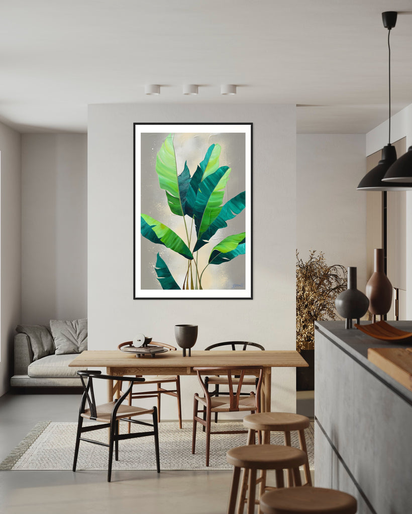 ‘Rainforest Glow' Fine Art Print by Jasmine Marshall, framed in black/oak. Premium Giclée print features green palm leaves on a neutral abstract painting. Displayed in a neutral kitchen with a white sofa and wooden table.