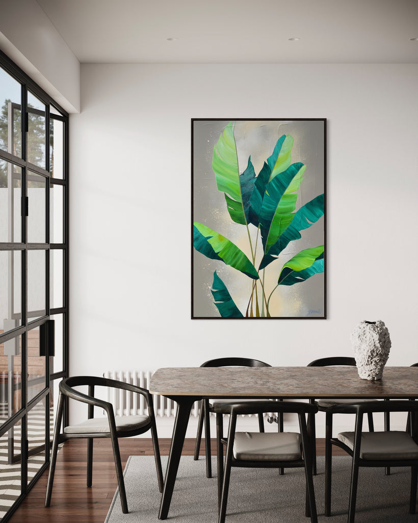 'Rainforest Glow' original painting on a cotton canvas by Jasmine Marshall, framed in black/oak. Features green palm leaves on a neutral abstract painting. Displayed in a dining room with black dining table and chairs and big glass doors.