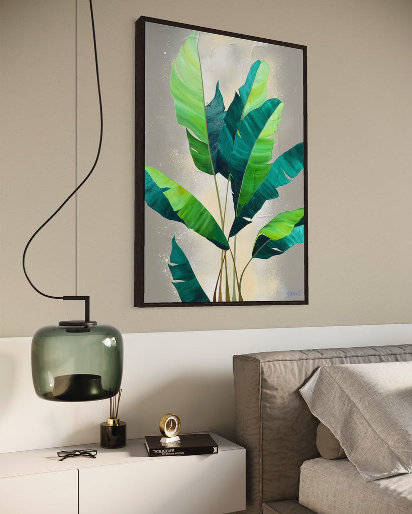 'Rainforest Glow' original painting on a cotton canvas by Jasmine Marshall, framed in black/oak. Features green palm leaves on a neutral abstract painting. Displayed in a neutral bedroom above a grey bed with green glass light.