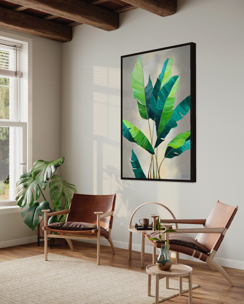 'Rainforest Glow' original painting on a cotton canvas by Jasmine Marshall, framed in black/oak. Features green palm leaves on a neutral abstract painting. Displayed in a neutral home interior with wooden ceiling beams, big window, brown chairs and a plant.