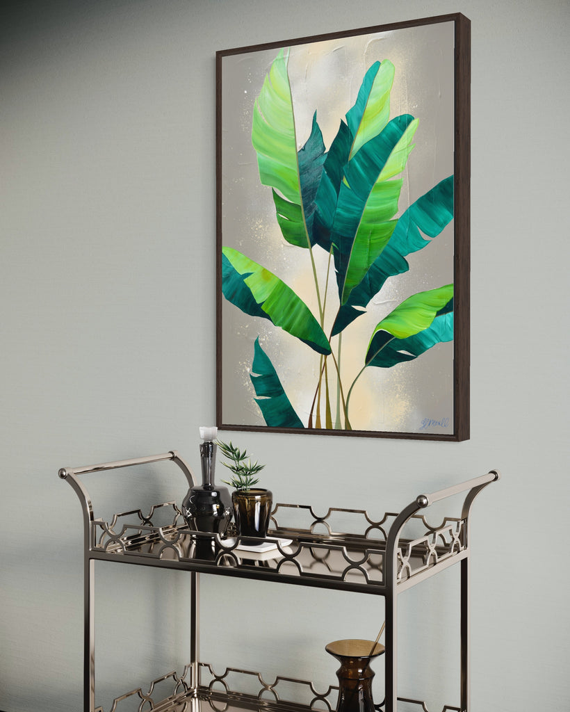 'Rainforest Glow' original painting on a cotton canvas by Jasmine Marshall, framed in black/oak. Features green palm leaves on a neutral abstract painting. Displayed on a wall above a mirrored bar cart.