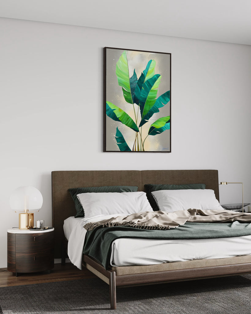 'Rainforest Glow' original painting on a cotton canvas by Jasmine Marshall, framed in black/oak. Features green palm leaves on a neutral abstract painting. Displayed in a bedroom with green bedding and wooden bed frame.