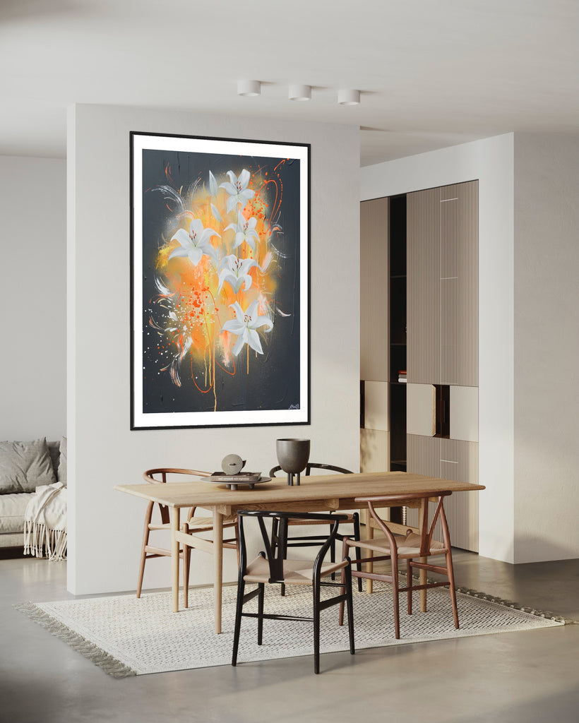 ‘Sweet Pollen' Fine Art Print by Jasmine Marshall, framed in black/oak. Premium Giclée print features white lilies on a grey textured background with pops of neon orange. Displayed in a neutral white kitchen with wooden table.