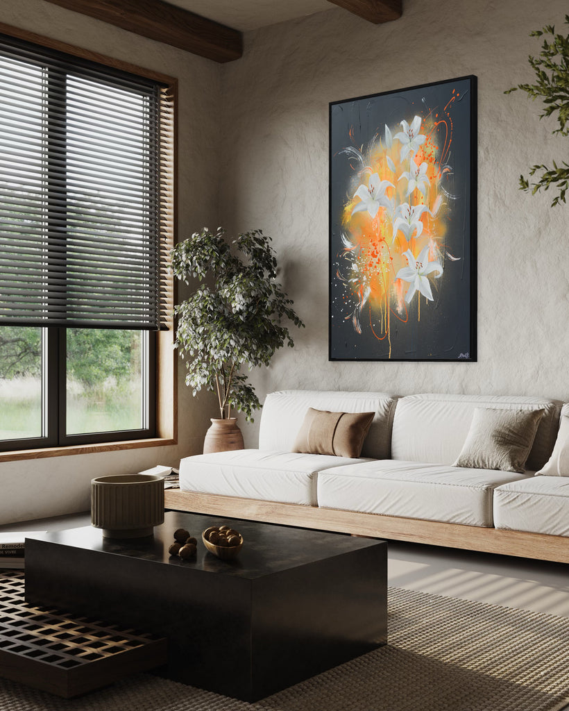 'Sweet Pollen' original painting on a cotton canvas by Jasmine Marshall, framed in black/oak. Features white lilies on a grey textured background with pops of neon orange. Displayed in a neutral living room with white sofa, wooden ceiling beams and plants.