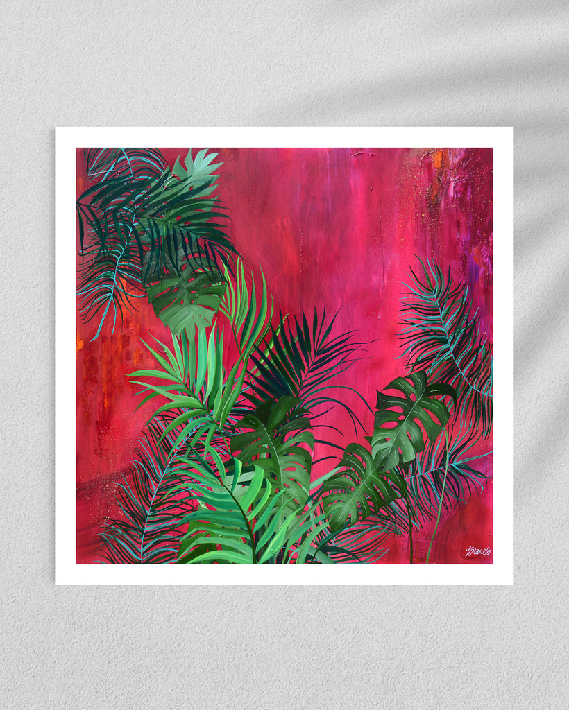 ‘The Foliage' Fine Art Print by Jasmine Marshall, framed in black/oak. Premium Giclée print features tropical leaves over an abstract pink, red and orange painting. Displayed in a gallery.