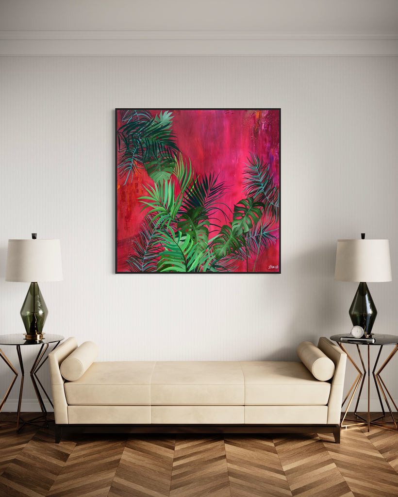 'The Foliage' original painting on a cotton canvas by Jasmine Marshall, framed in black/oak. Features tropical leaves over an abstract pink, red and orange painting Displayed in a neutral home interior with wooden floor and white sofa.