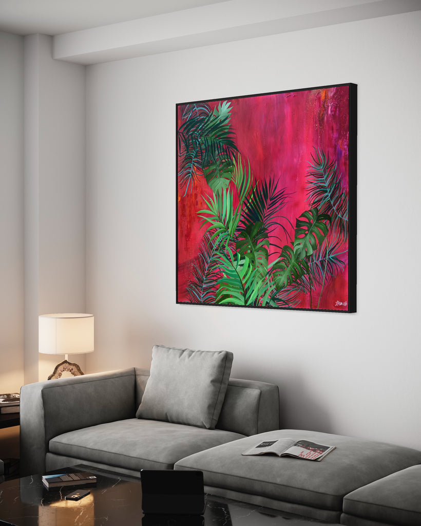 'The Foliage' original painting on a cotton canvas by Jasmine Marshall, framed in black/oak. Features tropical leaves over an abstract pink, red and orange painting Displayed in a neutral home interior with grey sofa, black marble coffee table, ipad and lamp.