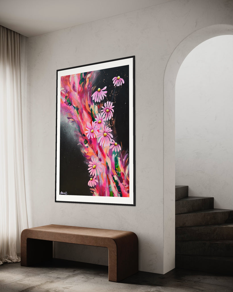 ‘The Laughter of Daisies' Fine Art Print by Jasmine Marshall, framed in black/oak. Premium Giclée print features pink daises on a colourful abstract details on a black background. Displayed in a neutral home interior.