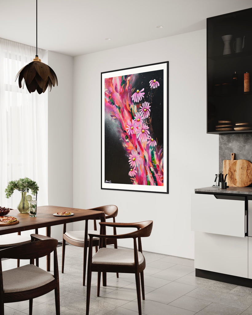 ‘The Laughter of Daisies' Fine Art Print by Jasmine Marshall, framed in black/oak. Premium Giclée print features pink daises on a colourful abstract details on a black background. Displayed in a kitchen with black units and wooden dining table.