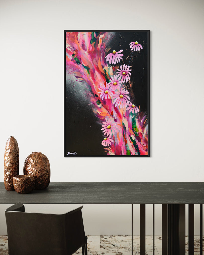 'The Laughter of Daisies' original painting on a cotton canvas by Jasmine Marshall, framed in black/oak. Features pink daises on a colourful abstract details on a black background. Displayed in a neutral home interior.