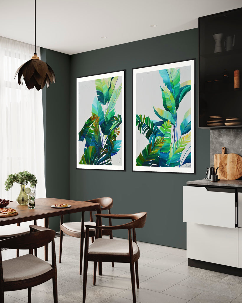 ‘Tropic Duo' Fine Art Print by Jasmine Marshall, framed in black/oak. Premium Giclée print features tropical blue and green leaves on a grey background. Displayed in a kitchen with green walls and wooden table.