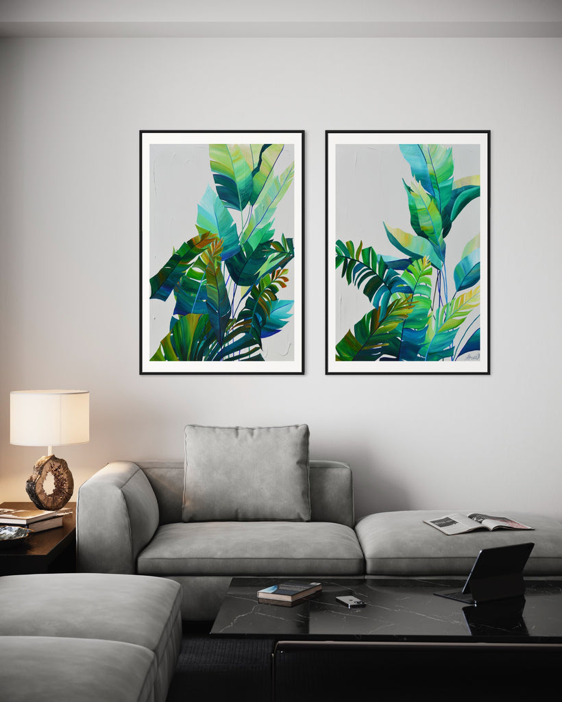 ‘Tropic Duo' Fine Art Print by Jasmine Marshall, framed in black/oak. Premium Giclée print features tropical blue and green leaves on a grey background. Displayed in a neutral home interior, grey sofa, black marble coffee table with books and an ipad on.