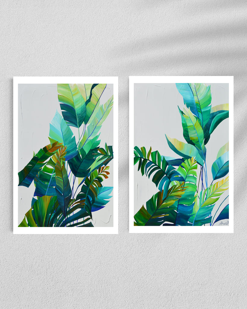 ‘Tropic Duo' Fine Art Print by Jasmine Marshall, framed in black/oak. Premium Giclée print features tropical blue and green leaves on a grey background. Displayed in a gallery.