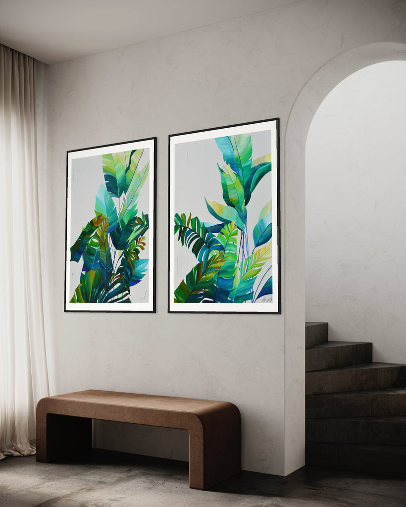 ‘Tropic Duo' Fine Art Print by Jasmine Marshall, framed in black/oak. Premium Giclée print features tropical blue and green leaves on a grey background. Displayed in a neutral home interior.