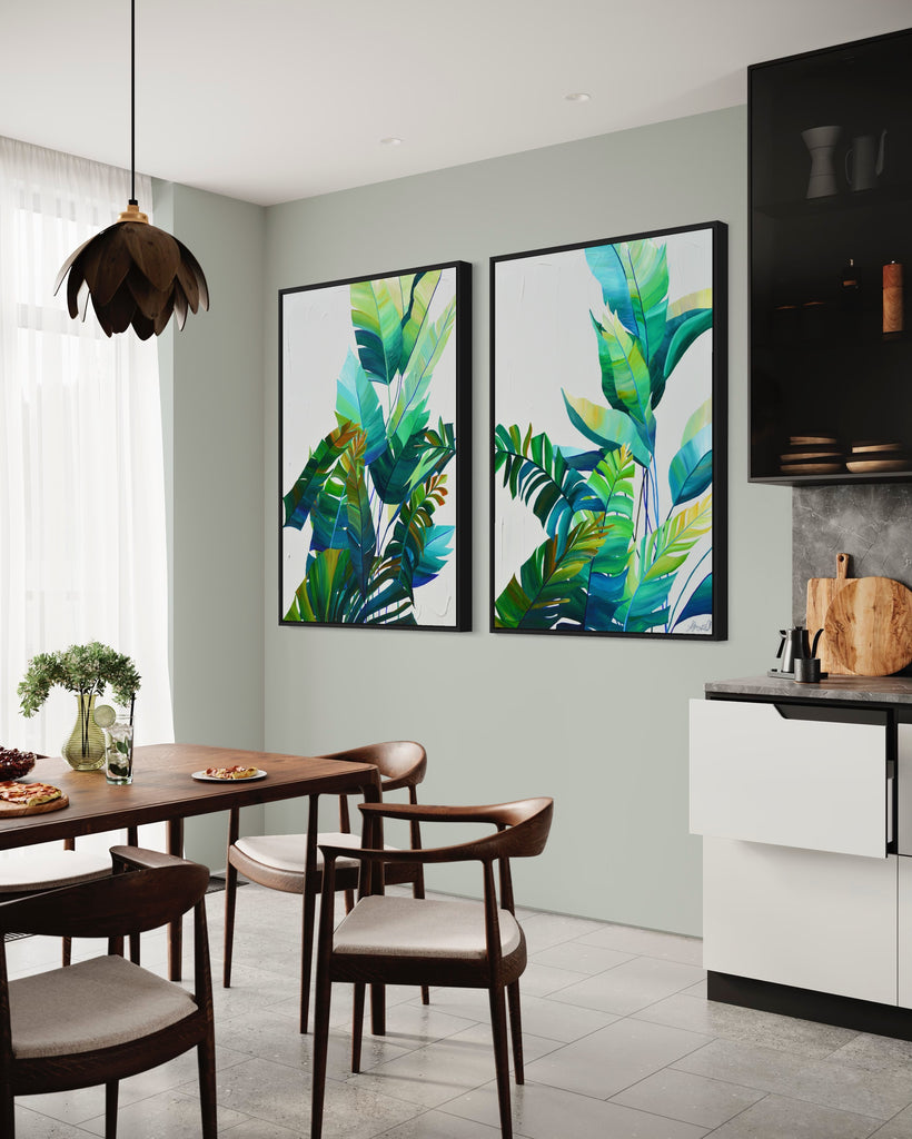 'Tropic Duo' original painting on a cotton canvas by Jasmine Marshall, framed in black/oak. Features tropical blue and green leaves on a grey background. Displayed in a neutral kitchen.