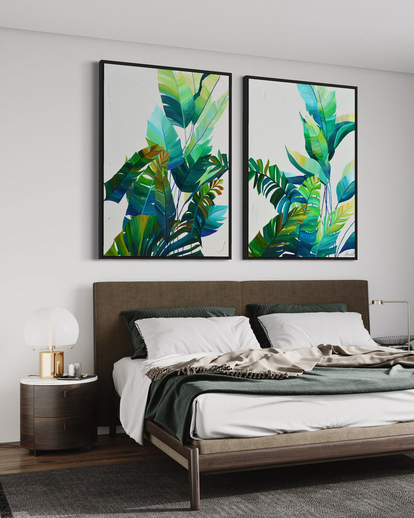 'Tropic Duo' original painting on a cotton canvas by Jasmine Marshall, framed in black/oak. Features tropical blue and green leaves on a grey background. Displayed in a neutral bedroom above a brown and green bed.