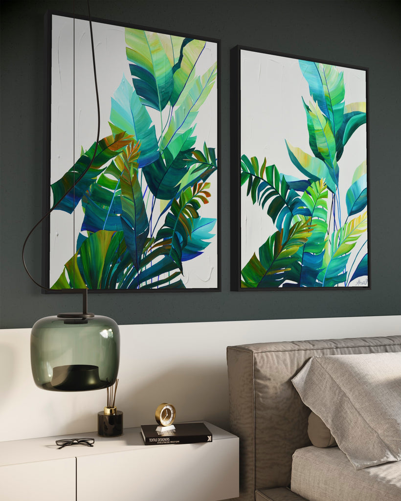 'Tropic Duo' original painting on a cotton canvas by Jasmine Marshall, framed in black/oak. Features tropical blue and green leaves on a grey background. Displayed on a green wall above a bed with a green glass lamp.