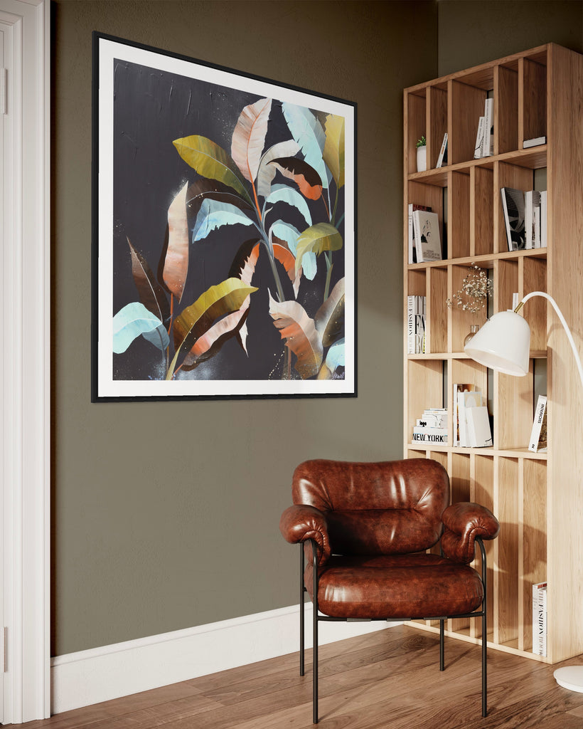 ‘Under the Canopy' Fine Art Print by Jasmine Marshall, framed in black/oak. Premium Giclée print features a palm tree on a brown background with abstract details. Displayed on a grey wall next to a wooden book shelf with a brown chair and white standing lamp.